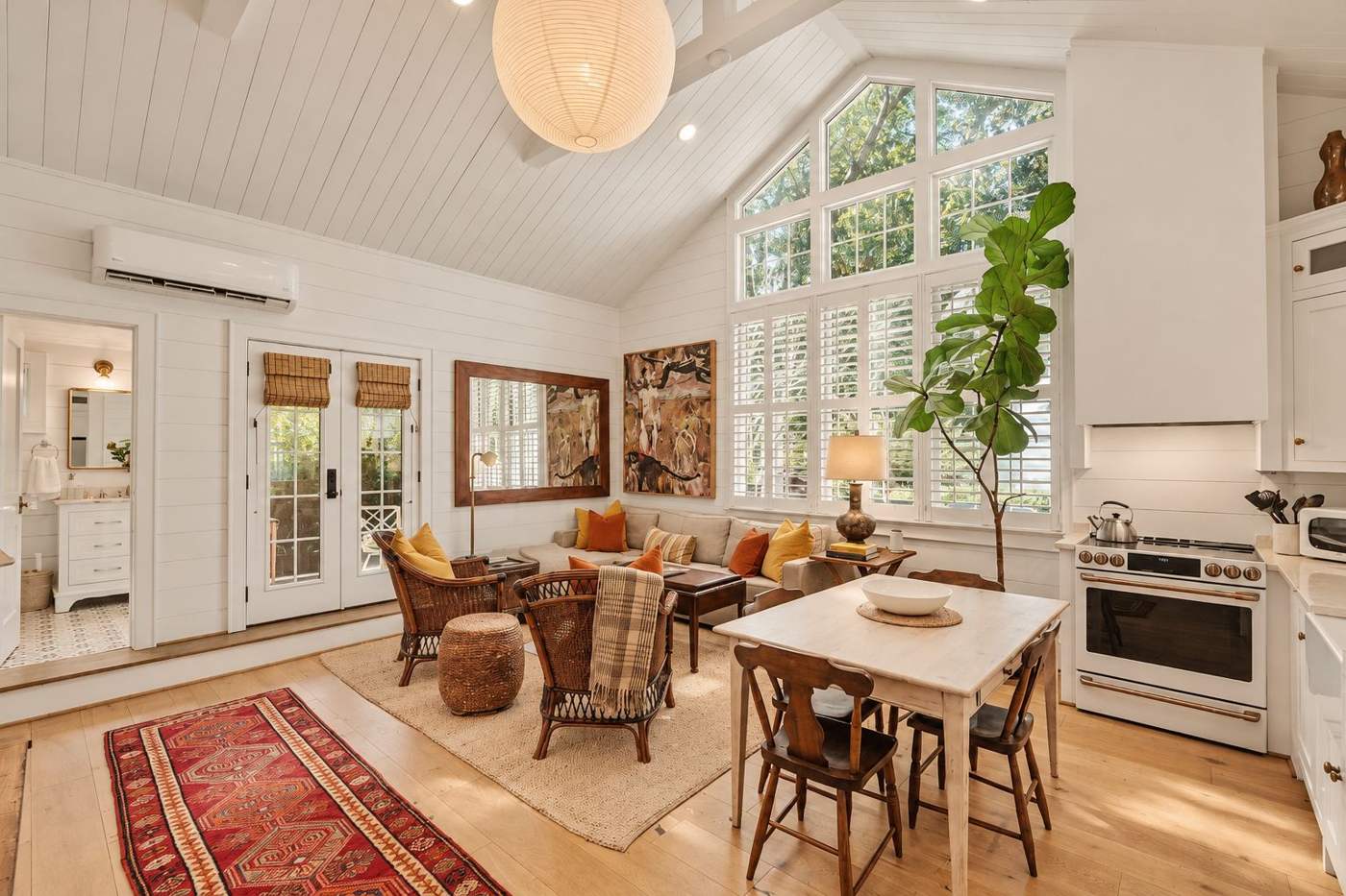 The cottage den with vaulted ceiling, dining table and kitchen